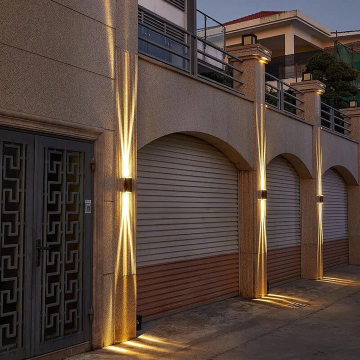 Row of wall lights washing beige pillars above garage doors at dusk