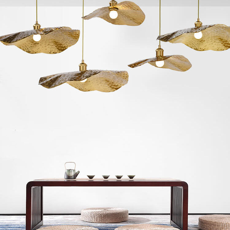 Warm gold lotus leaf pendant lights glowing above a lakeside dining space