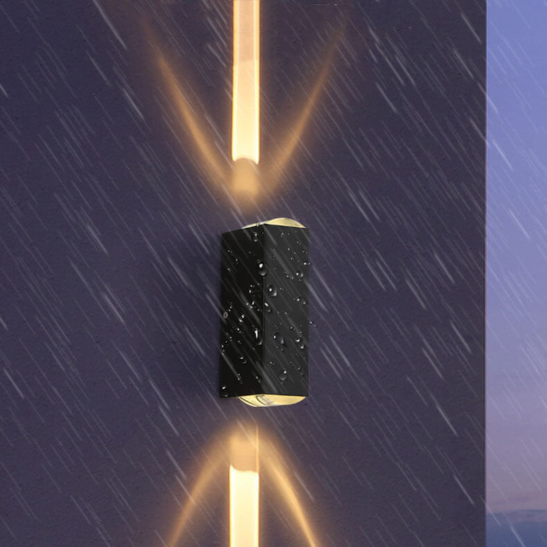 Black wall sconce beaded with water and glowing up and down in the rain