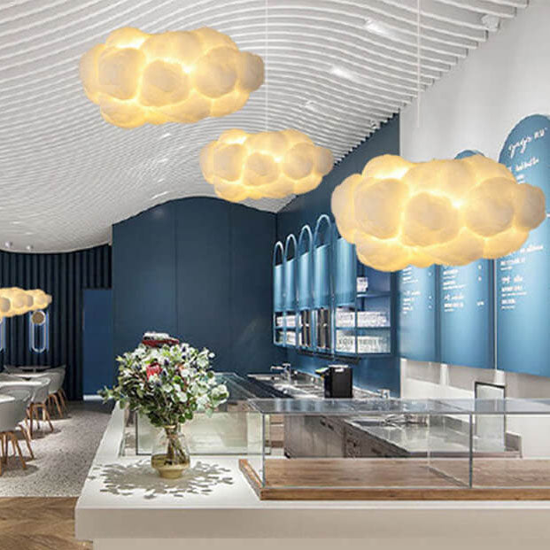 Cluster of glowing cloud pendant lights in a blue-toned cafe interior
