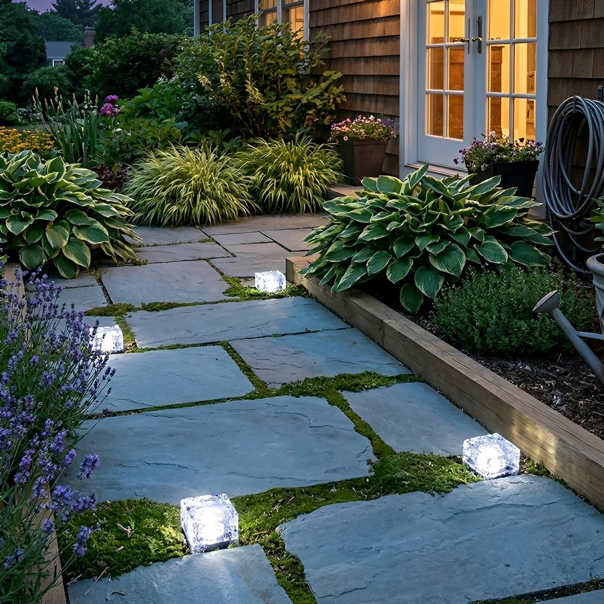 White cube lights lining a paved path beside a lit house at twilight