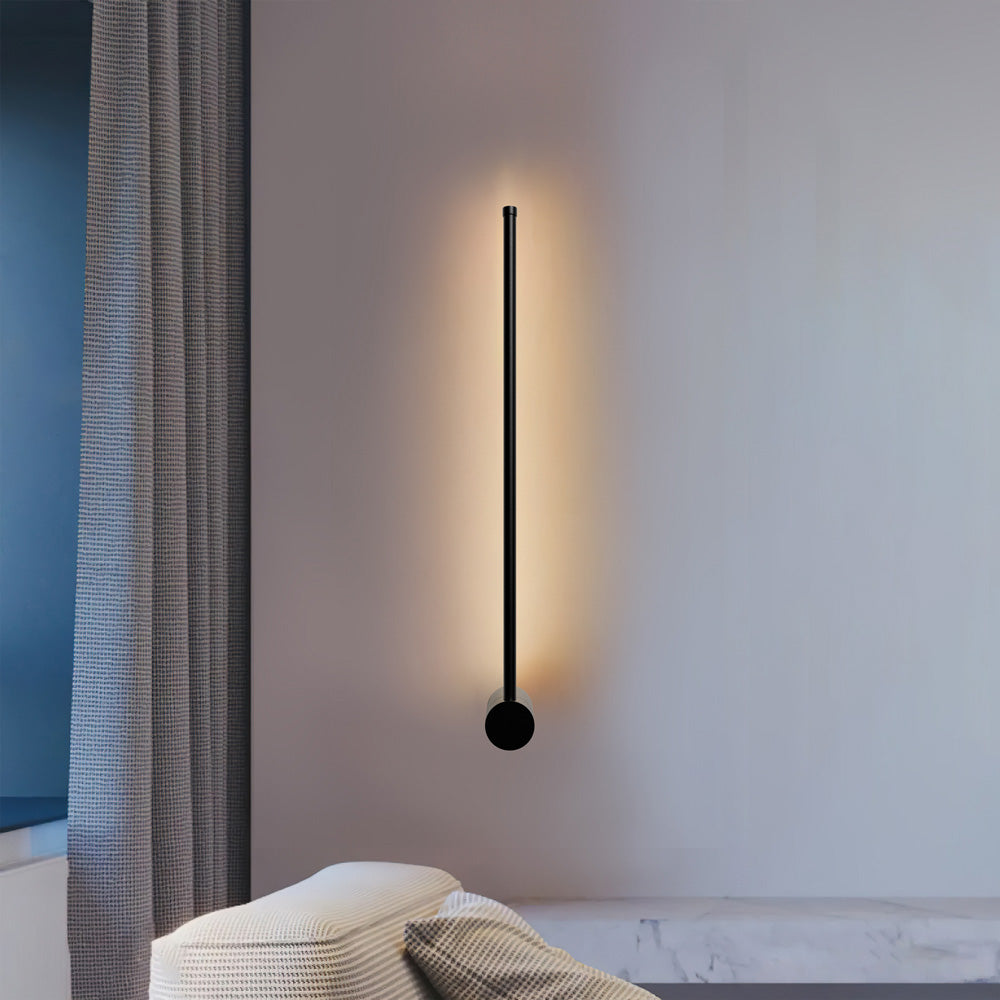 Slim vertical black wall sconce on a beige bedroom wall