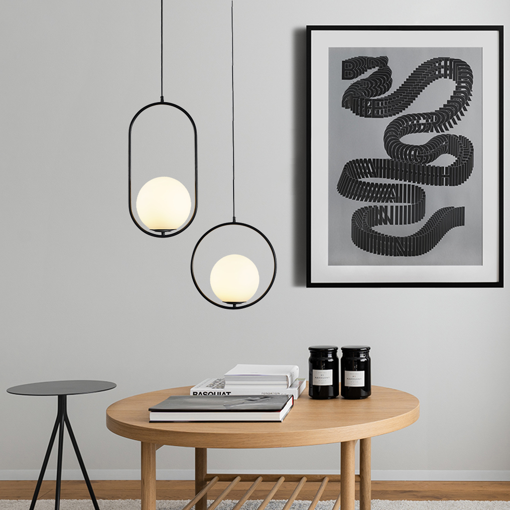 Two black frame glass globe pendants hung at different drops in a cream living room
