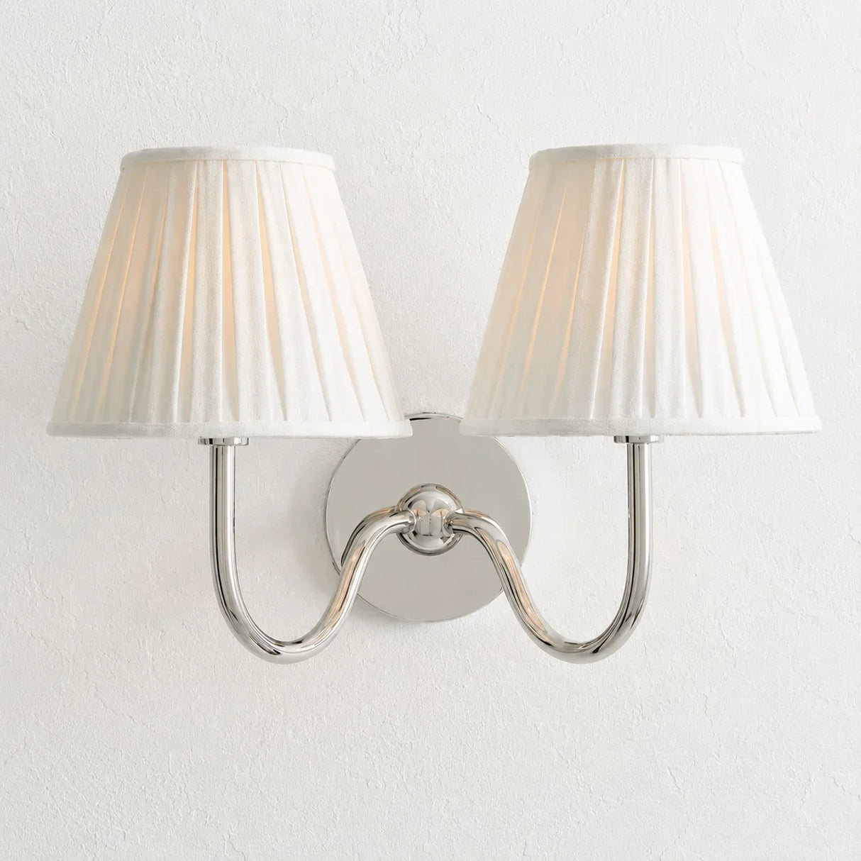 Chrome-finish wall sconce with pleated linen shade and slim curved arm, white shade lit shot 25