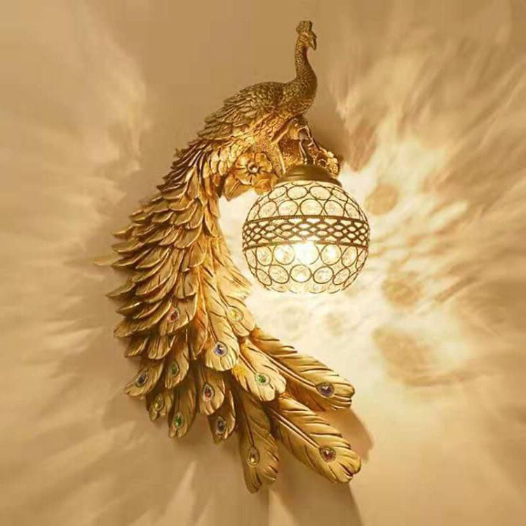Ivory peacock wall sconce facing left with a lit crystal ball shade on white