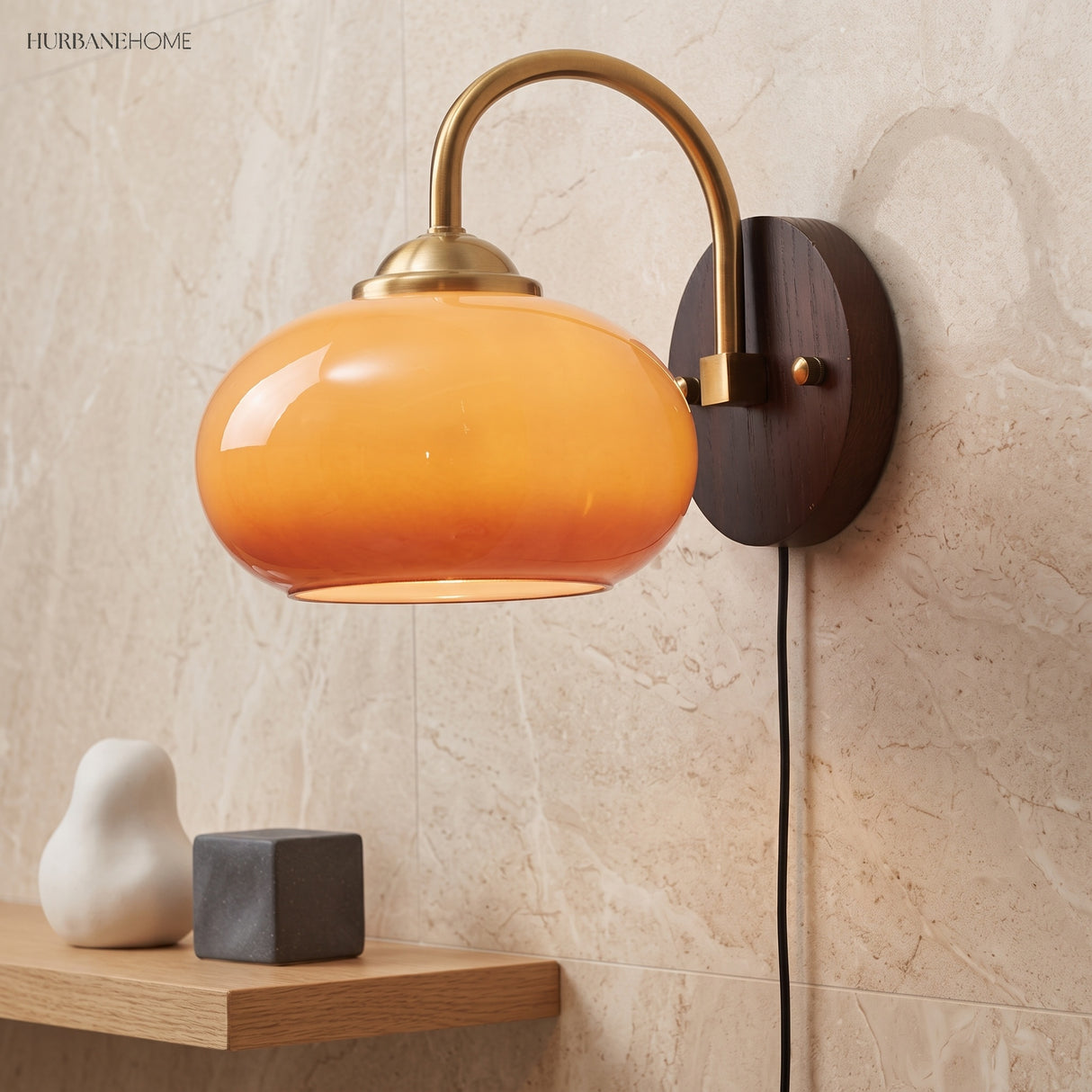 Amber oval glass sconce mounted above a wood shelf with stone decor