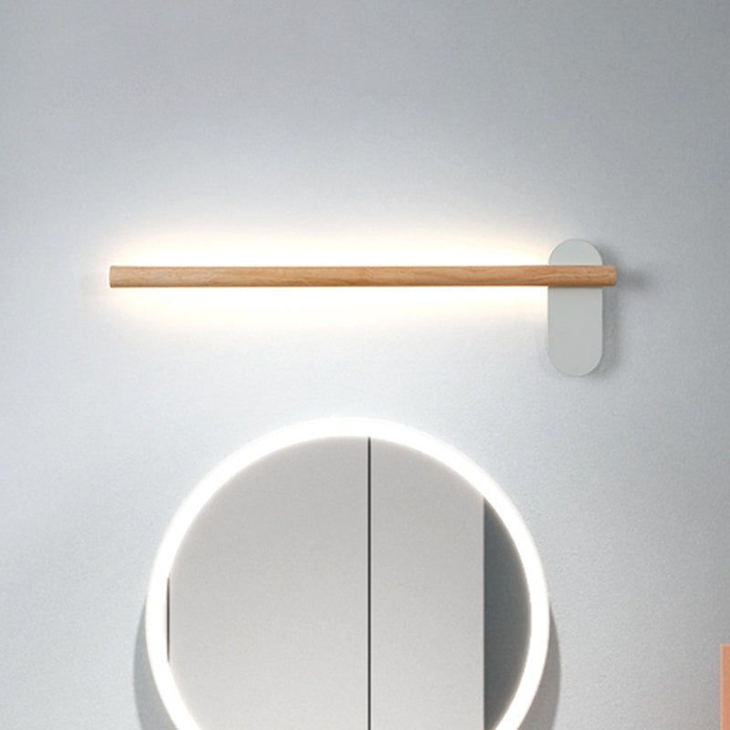Slim wood vanity light lit above a round mirror on plain grey