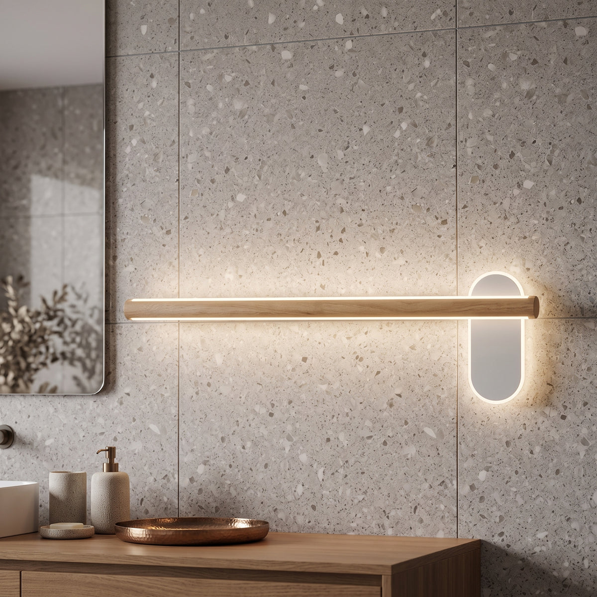 Slim wood vanity light lit on a terrazzo wall above a basin