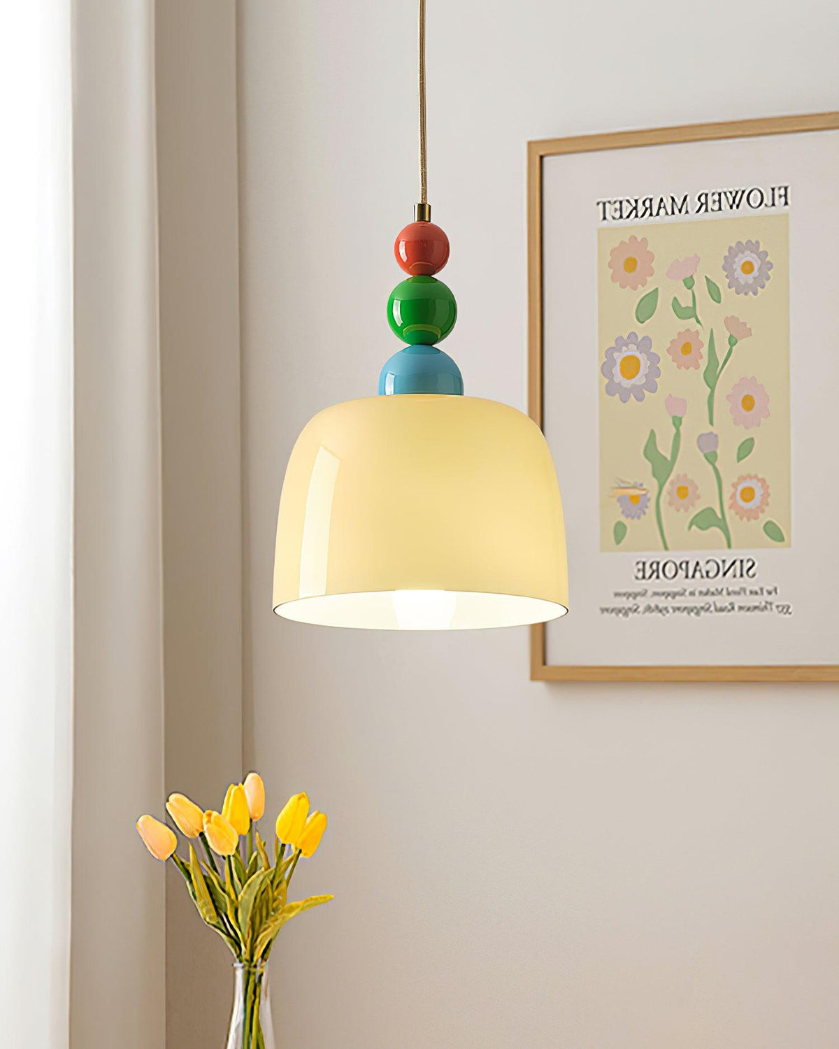 Beaded pendant beside a framed floral print with yellow tulips beneath it