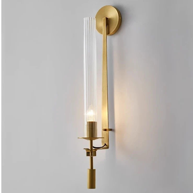 Gold fluted glass sconce lit tall against a plain background