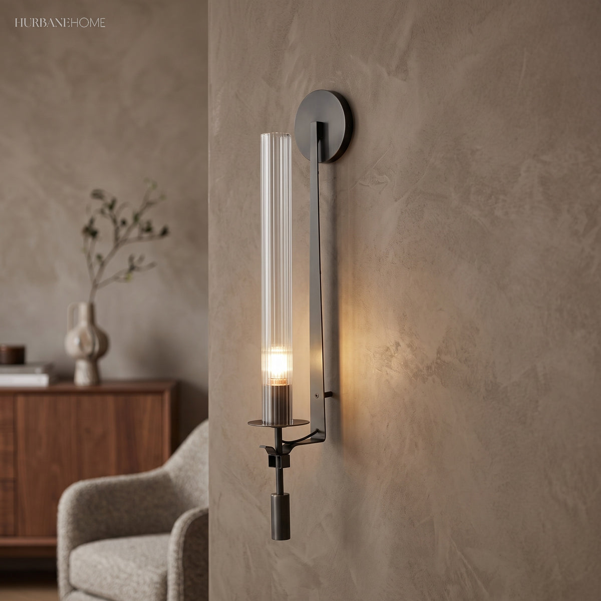 Black fluted glass sconce lit warm on a plaster wall