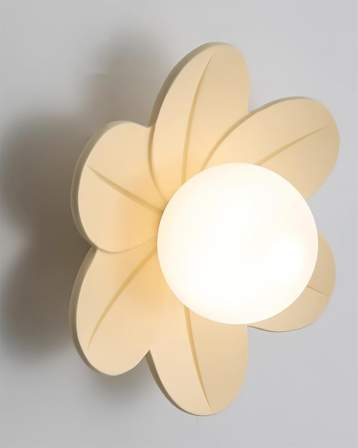 Close view of the beige petal fitting lit, with the globe glowing at the centre