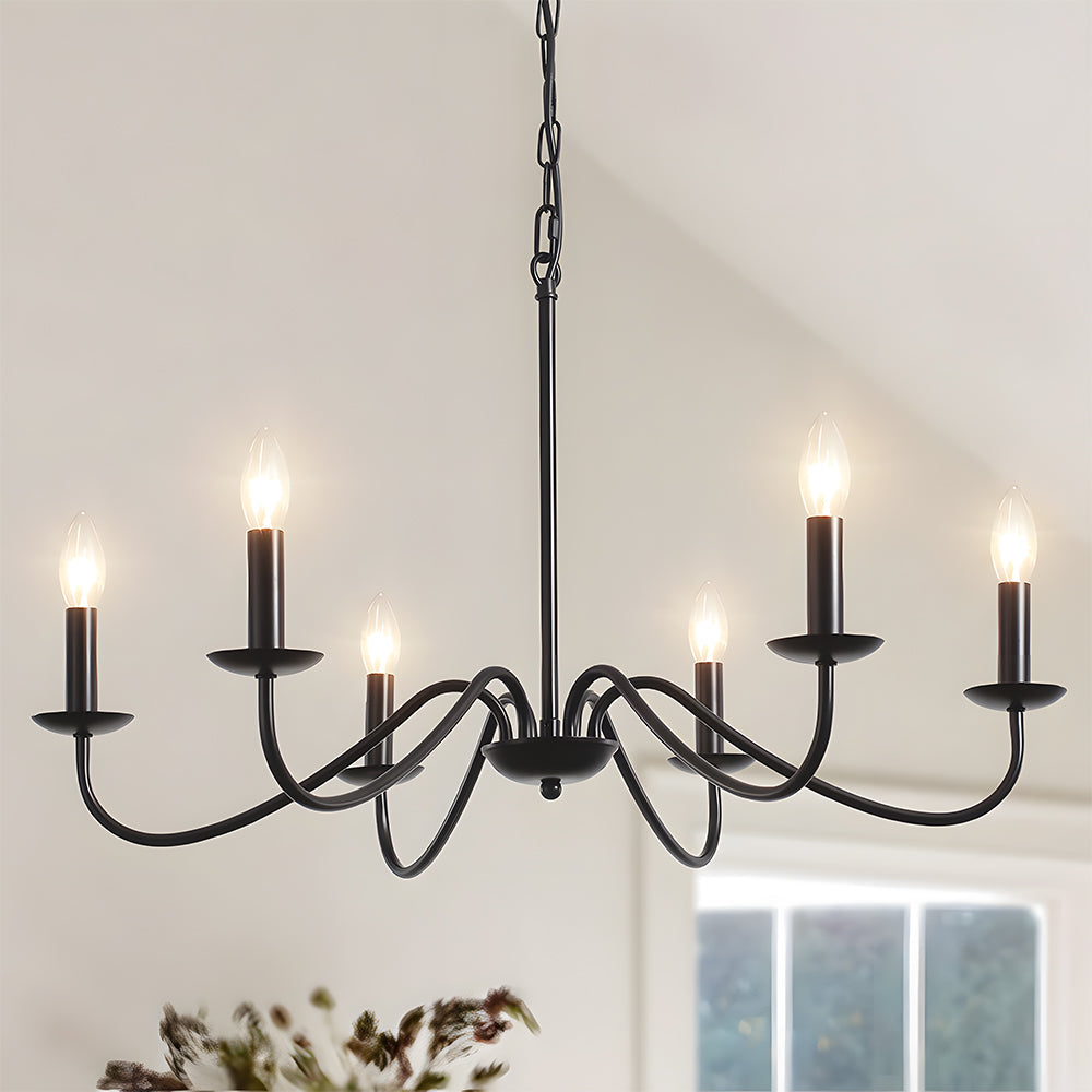 Six light black iron candle chandelier hanging under a vaulted white ceiling