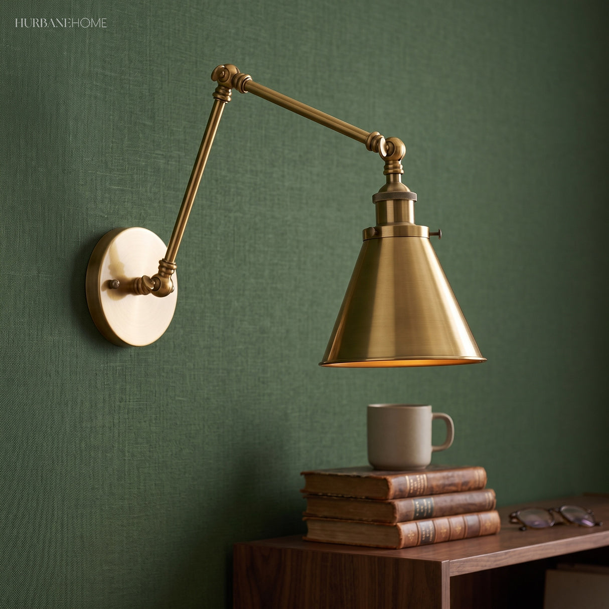 Brass swing arm sconce with a cone shade on a dark green wall