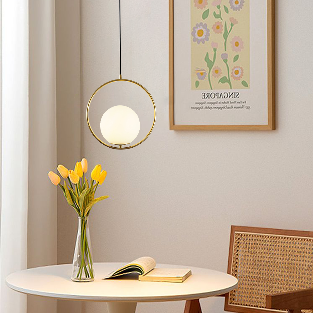 Gold round frame glass globe pendant over a dining table with yellow tulips