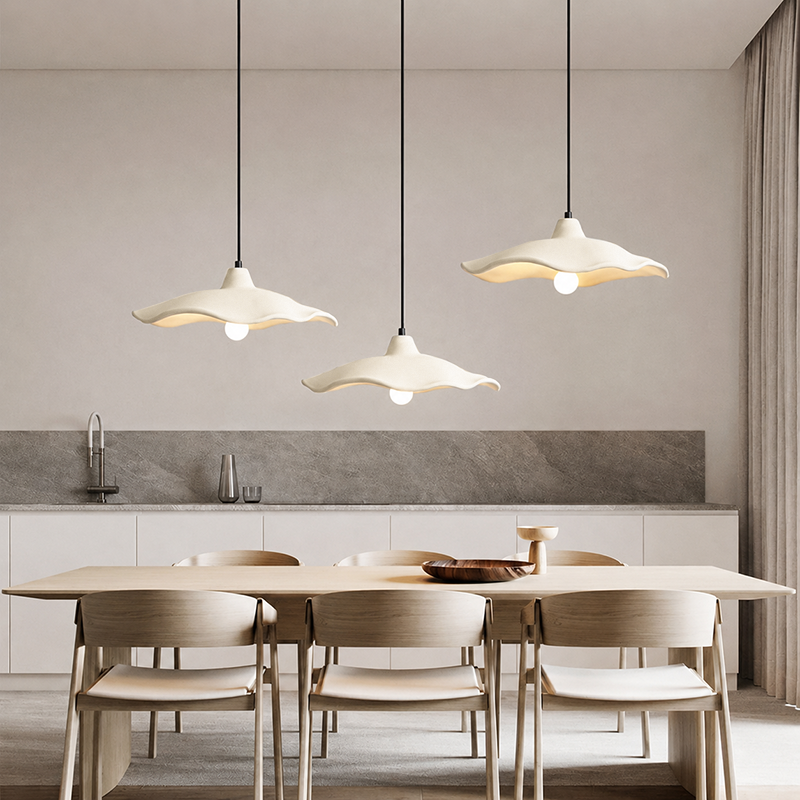 Off-white cement pendant light lit above a dark timber tea setting
