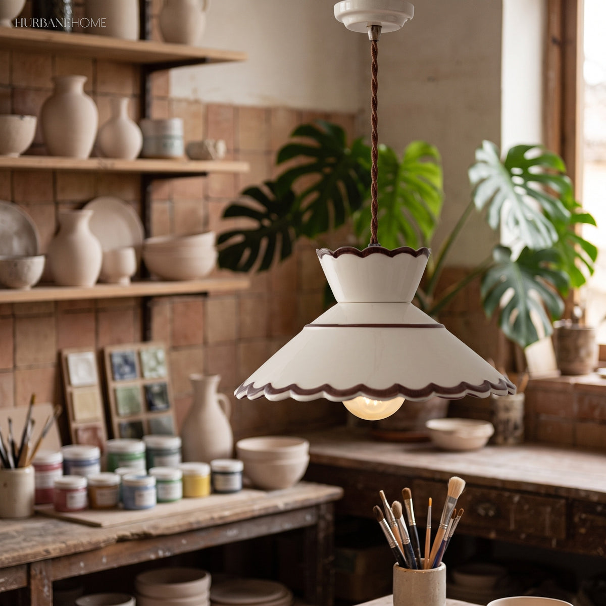 Ivory scalloped ceramic pendant lit above a potters workbench
