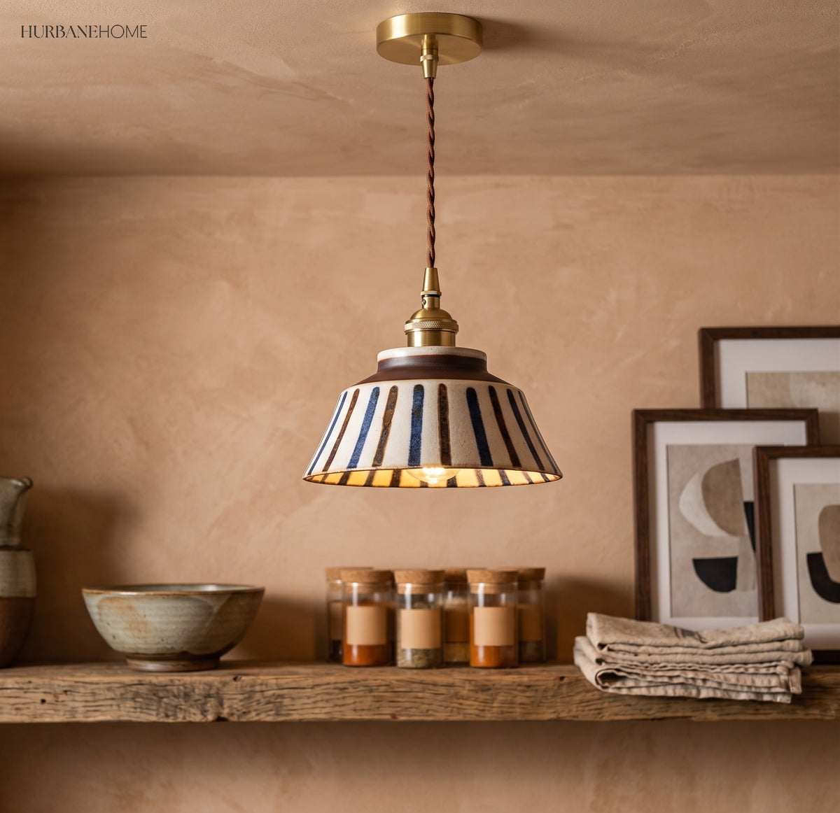 Striped ceramic pendant lit above a shelf of pots and candles