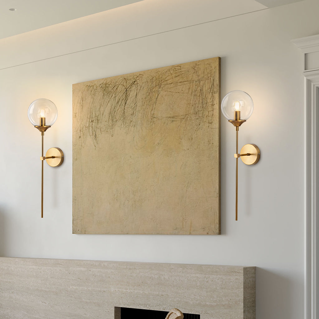 Clear glass globe wall sconce on a brass stem front view