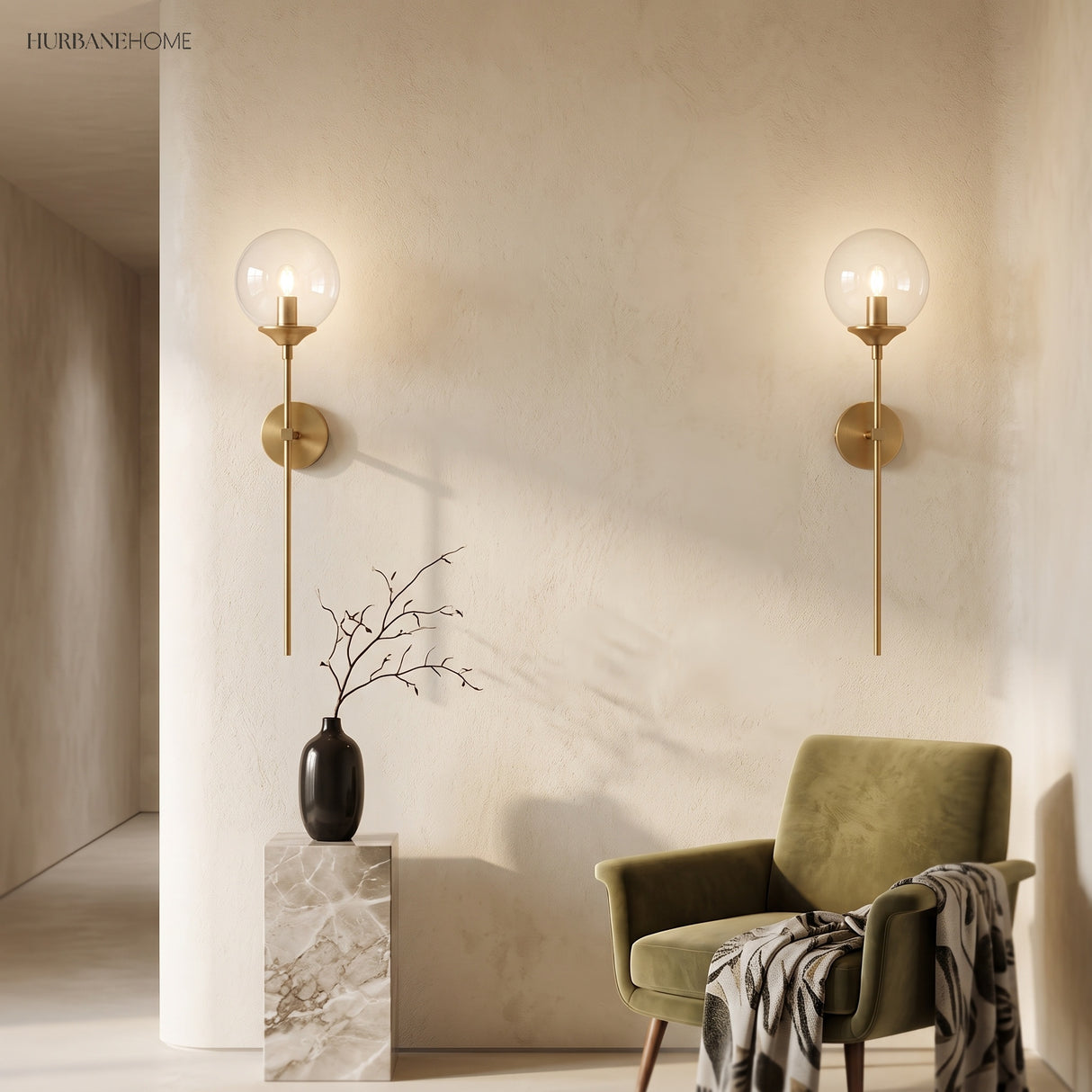 Two clear glass globe wall sconces flanking a beige wall above a green chair