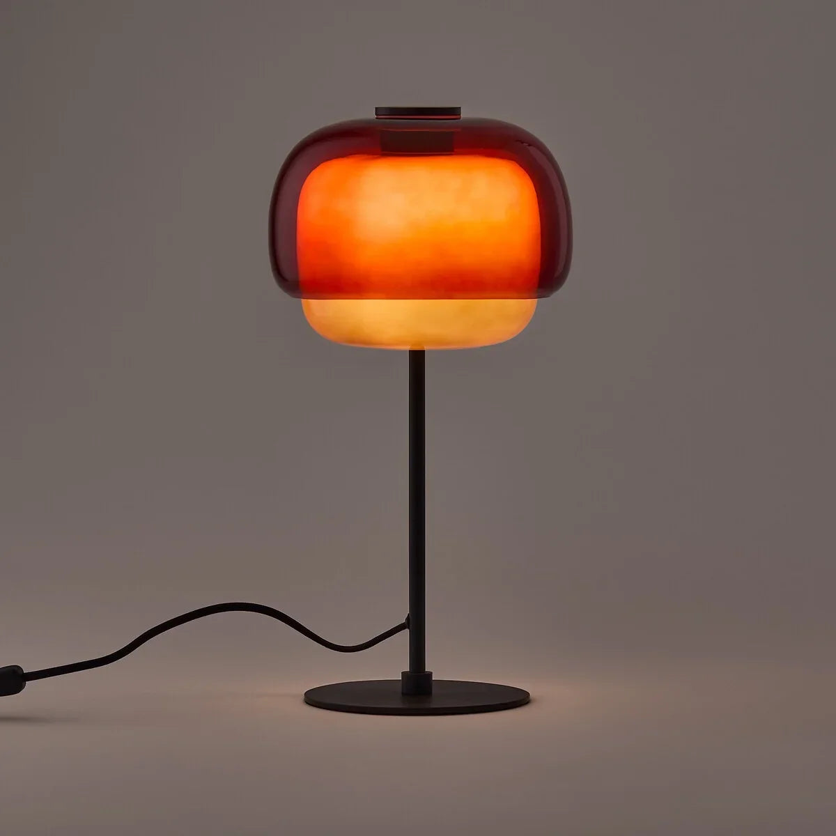 Red colored glass table lamp with domed shade and dark metal base