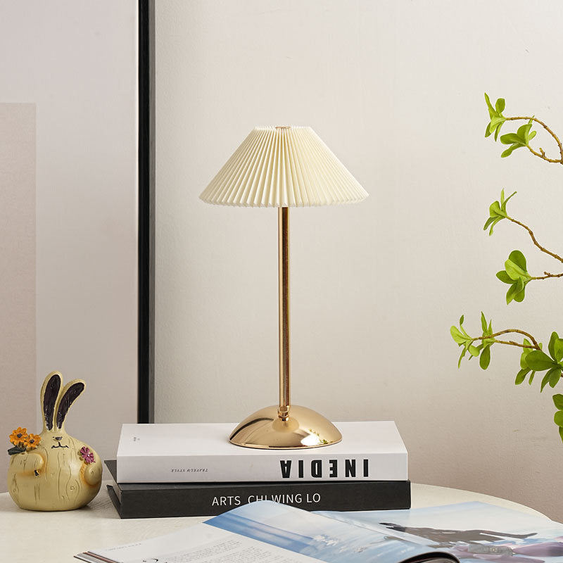 Gold table lamp with a rounded dome base and cream shade