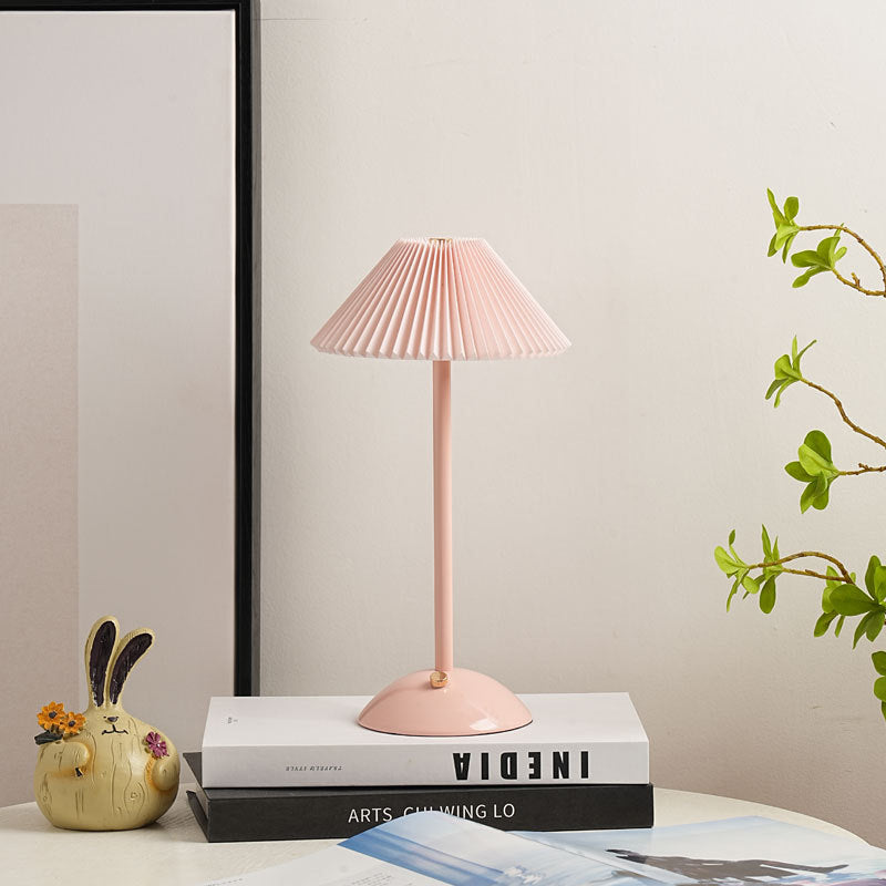 Soft pink table lamp with matching pleated shade on a side table