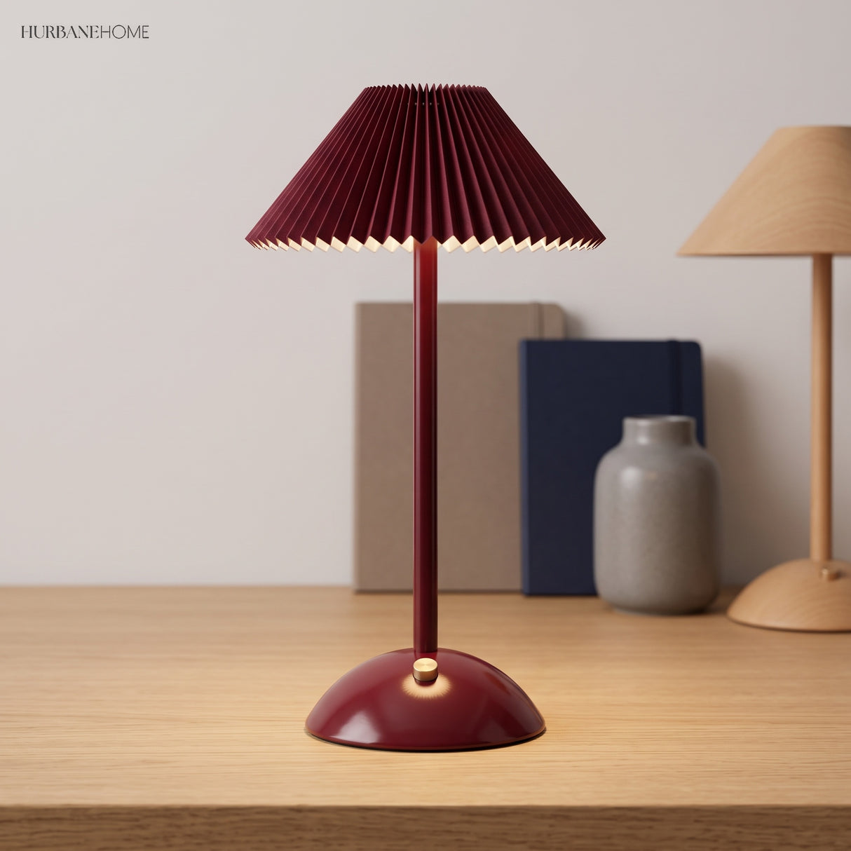 Red pleated table lamp on a wood desk with a base control knob