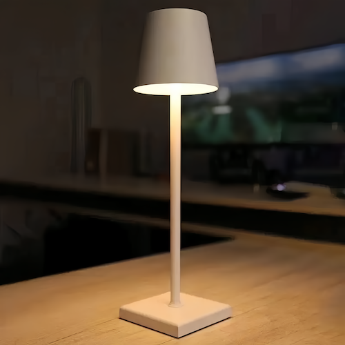 White cordless table lamp lit against a dark evening background