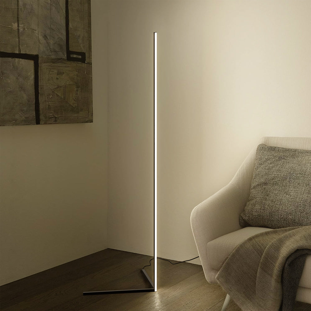 Slim floor lamp lighting a corner beside an armchair and large abstract painting