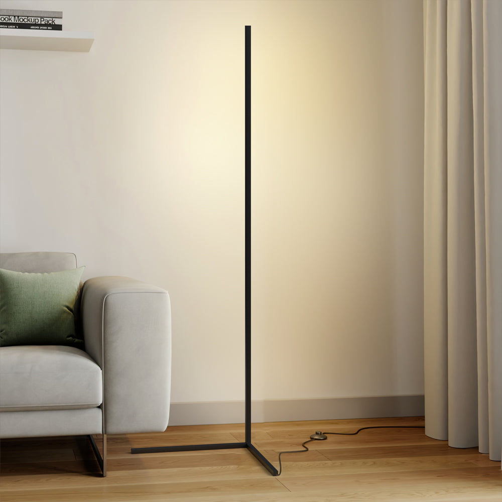 Black floor lamp with warm glow next to a grey sofa and curtain