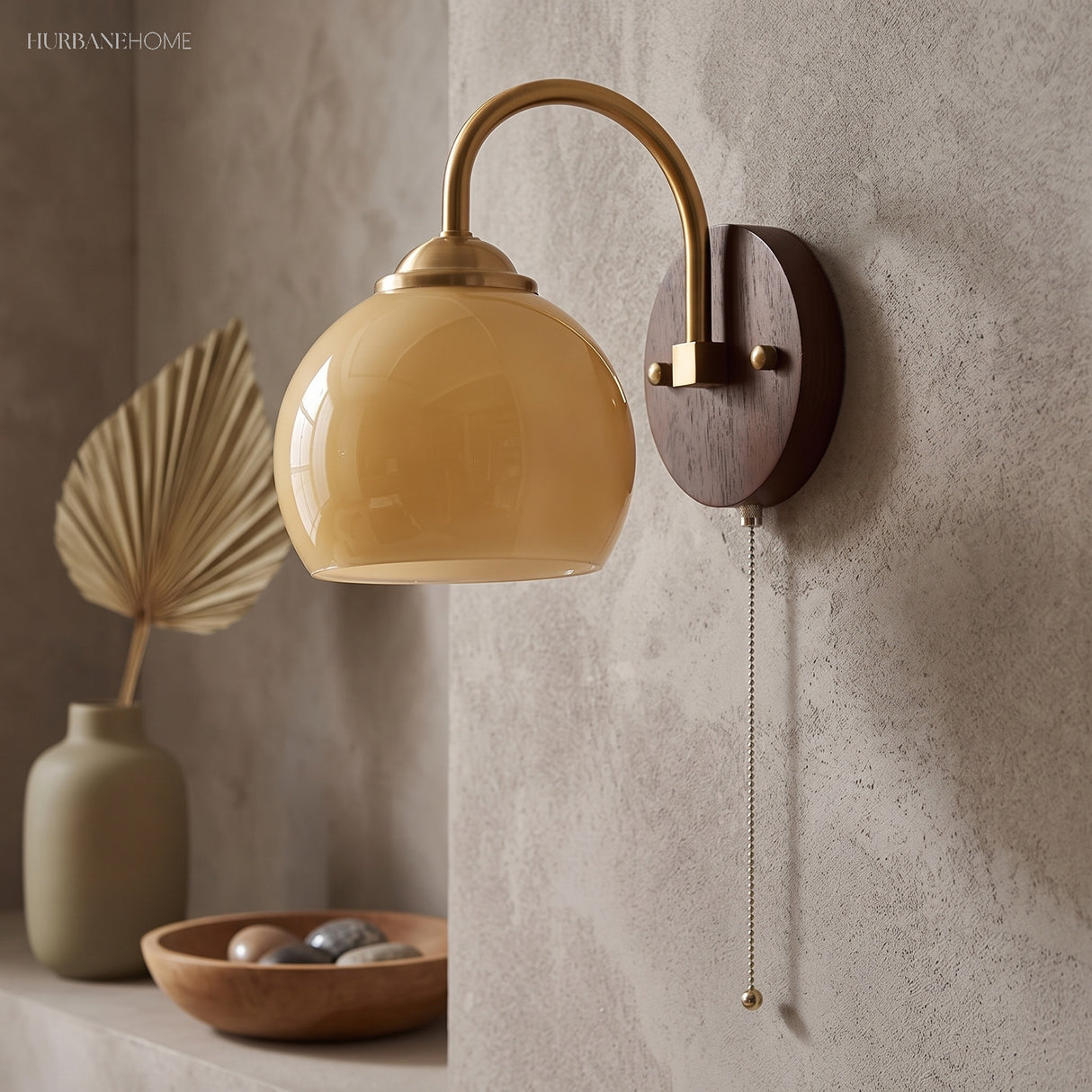 Cream dome glass sconce on textured plaster beside a dried palm leaf