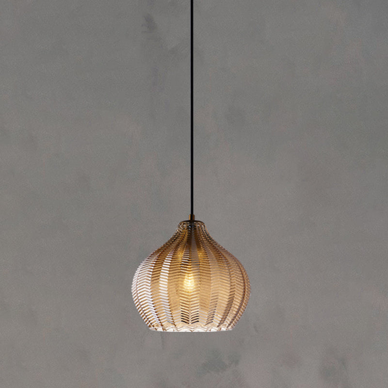 Cognac ribbed pendant with a rounded shade lit on concrete