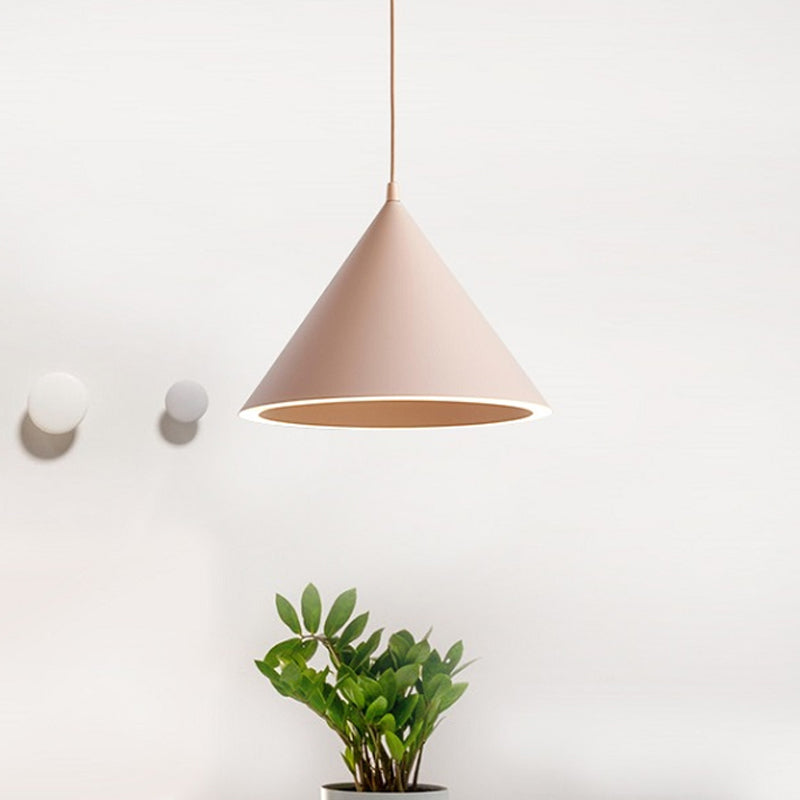 Pink cone pendant lit on a white wall above two small pots