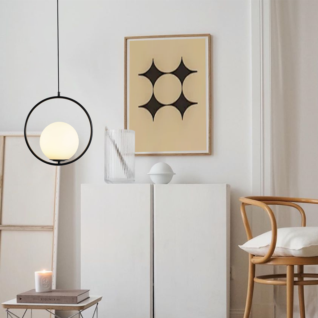 Gold oval frame glass globe pendant glowing above a bedside table with flowers