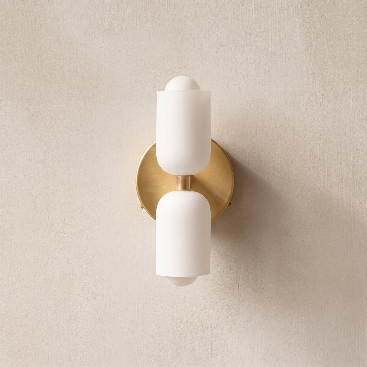 Acrylic up and down wall light with brass backplate on a plaster wall