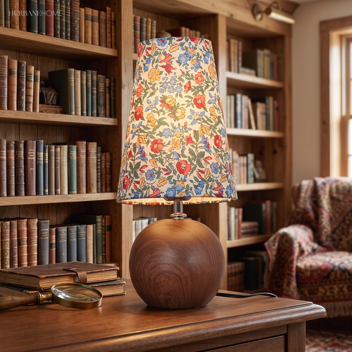 Floral shade table lamp on a dark wood desk in front of full bookshelves
