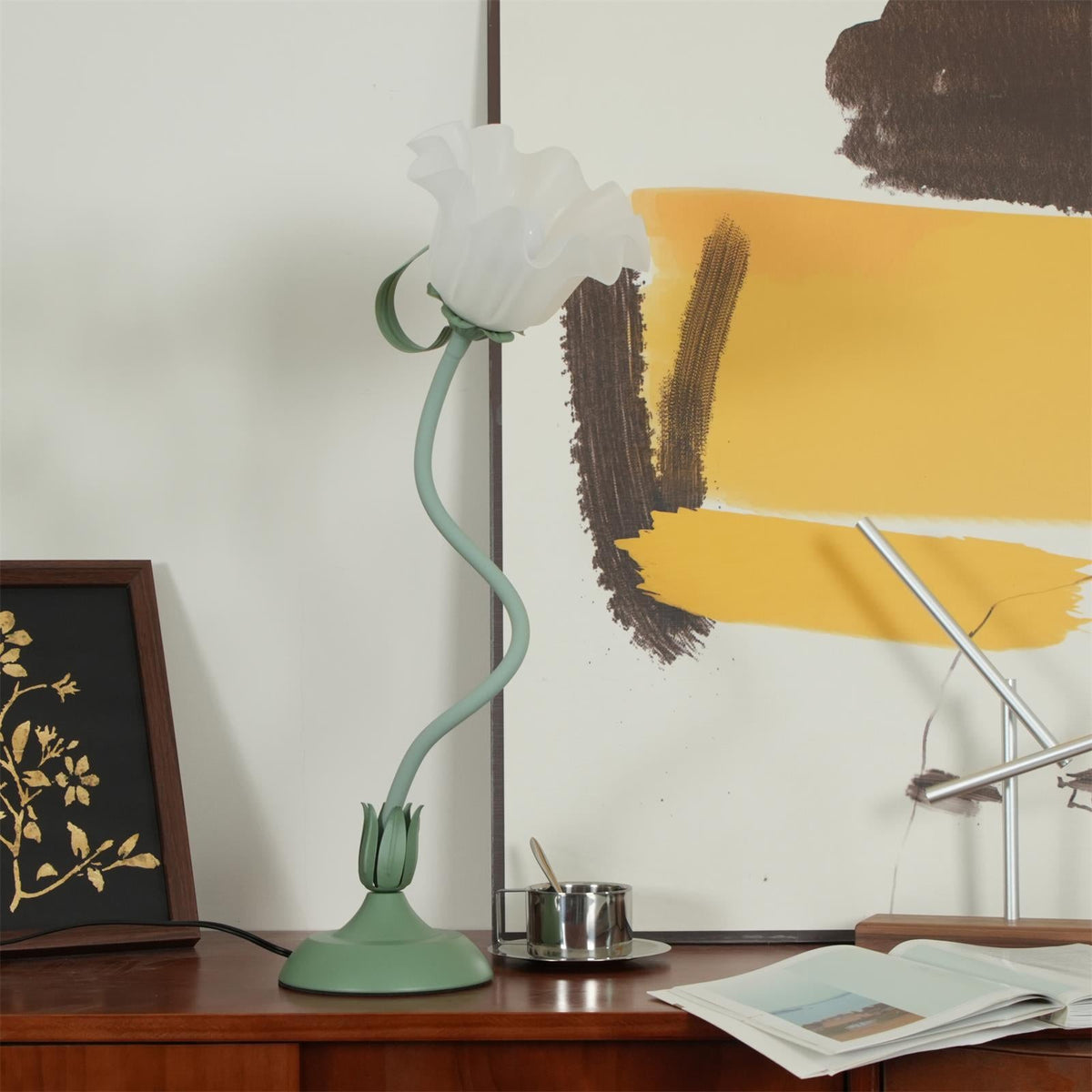 Side angle of the flower table lamp on a sideboard with artwork behind it