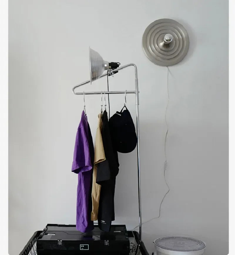 Silver ripple disc light beside a garment rail on a white wall