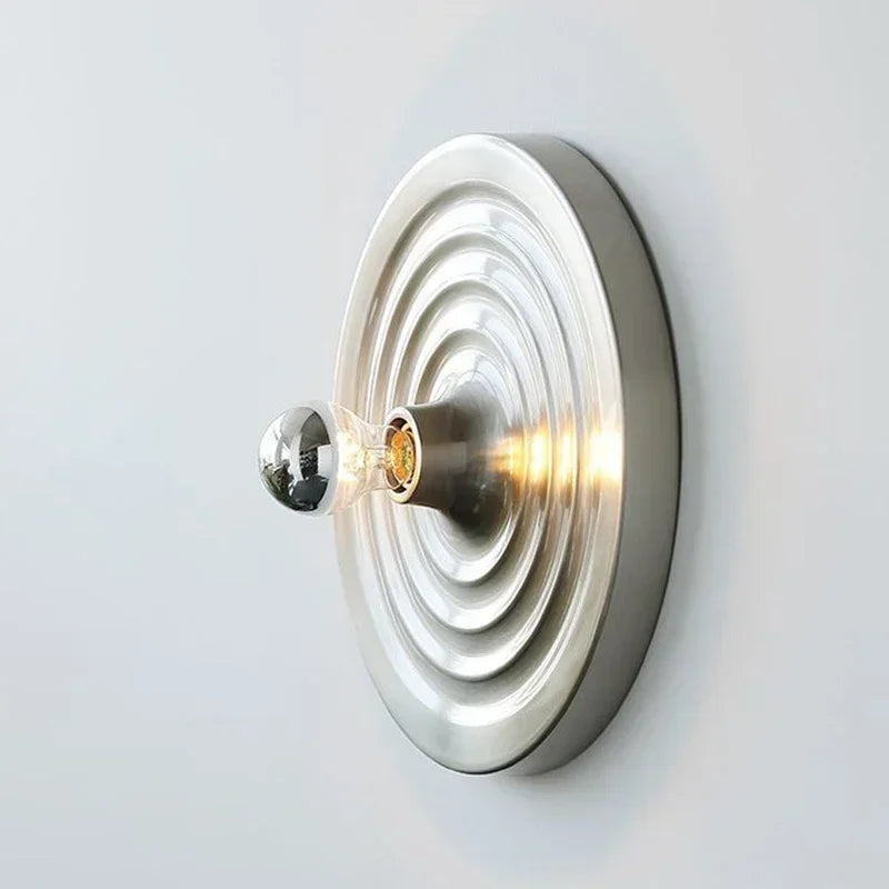 Silver ripple disc light lit warm with the bulb glowing at the centre
