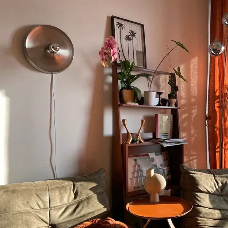 Silver disc lights on a wall in a warm room with a bookshelf