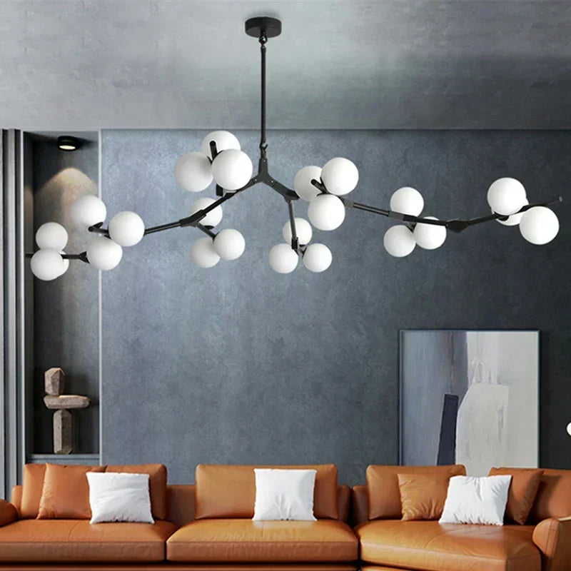 Black branch chandelier with glass globes above a burnt orange sofa