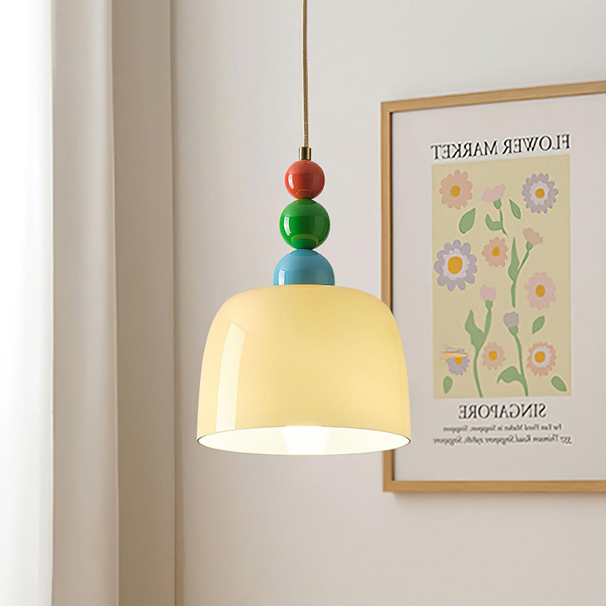 Beaded pendant hanging beside a framed flower market print on a pale wall
