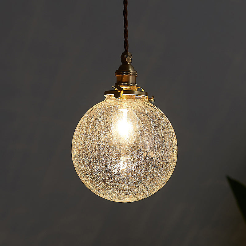Crackle glass sphere pendant glowing warm against a dark grey background