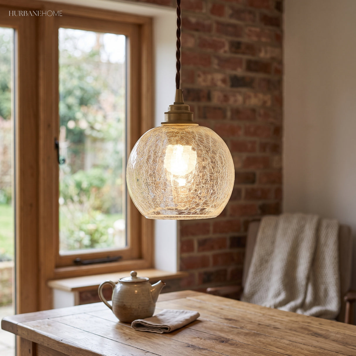 Squat crackle glass pendant over a wooden table by a brick wall