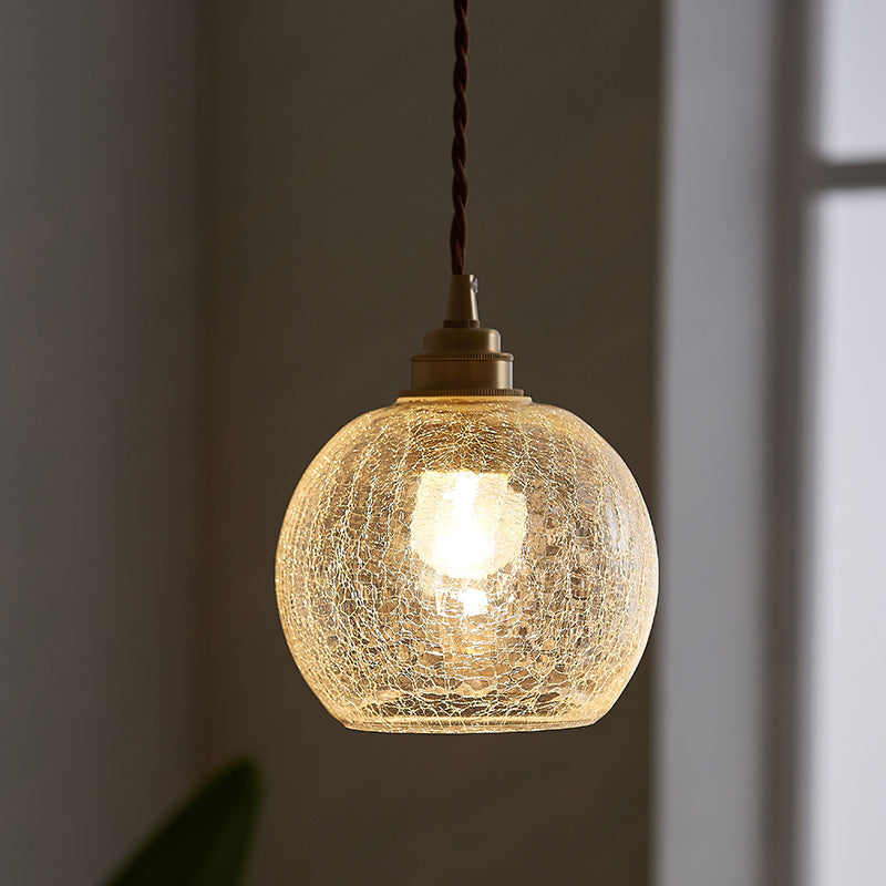 Squat crackle glass globe lit warm on an olive toned wall