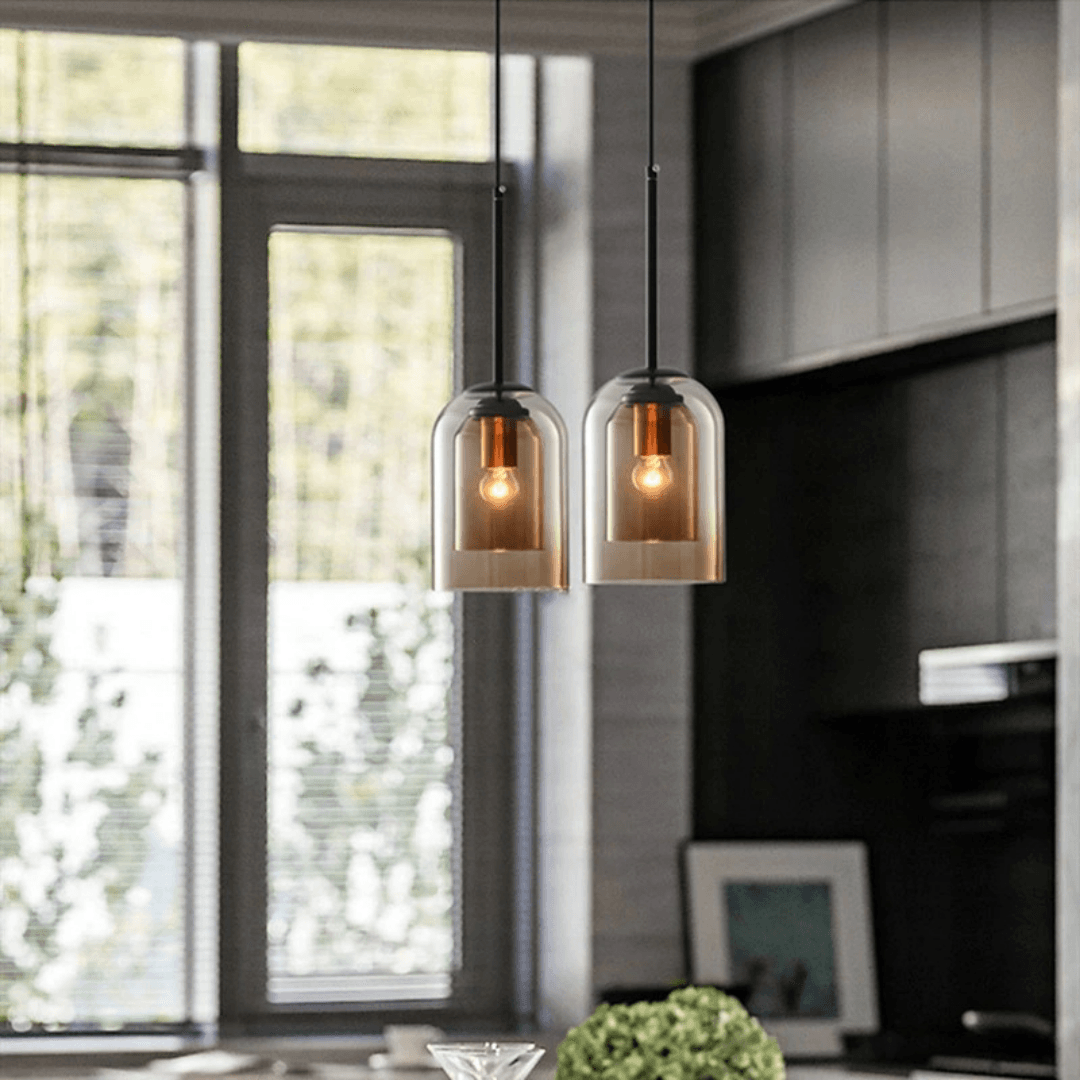 Two glass pendants hung by a window in a dark kitchen