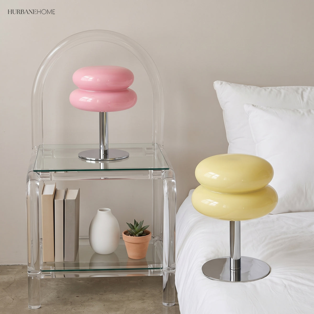 Pink and yellow stacked glass lamps lit beside a bed and clear chair