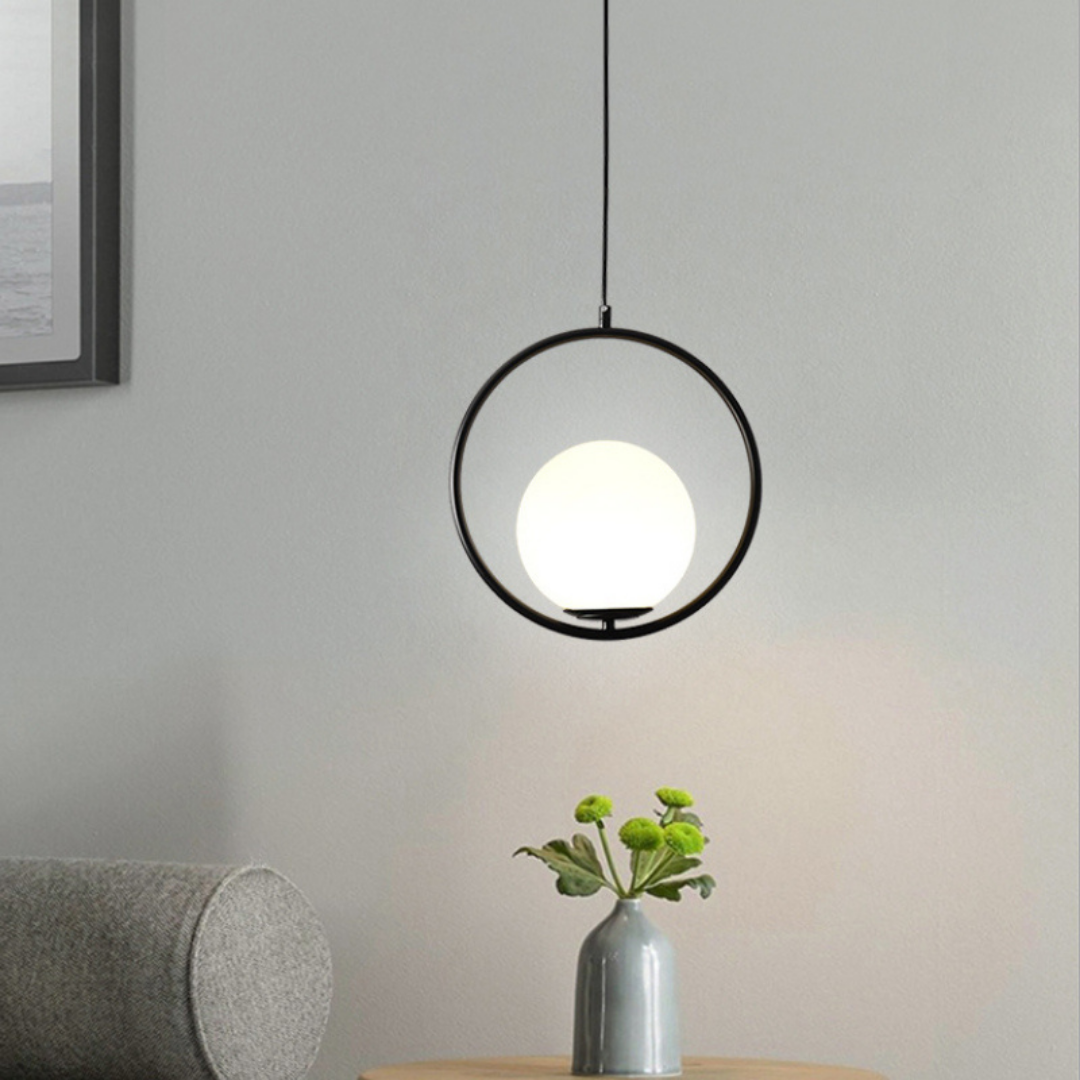 Black round hoop pendant lit above a table with a small vase