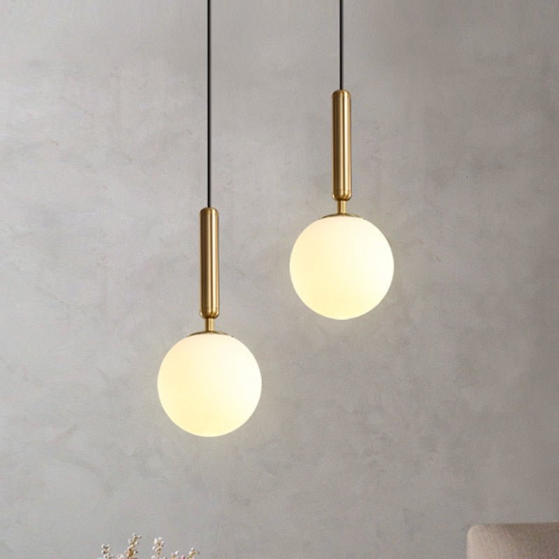 Two globe pendants lit warmly at different heights on a grey wall